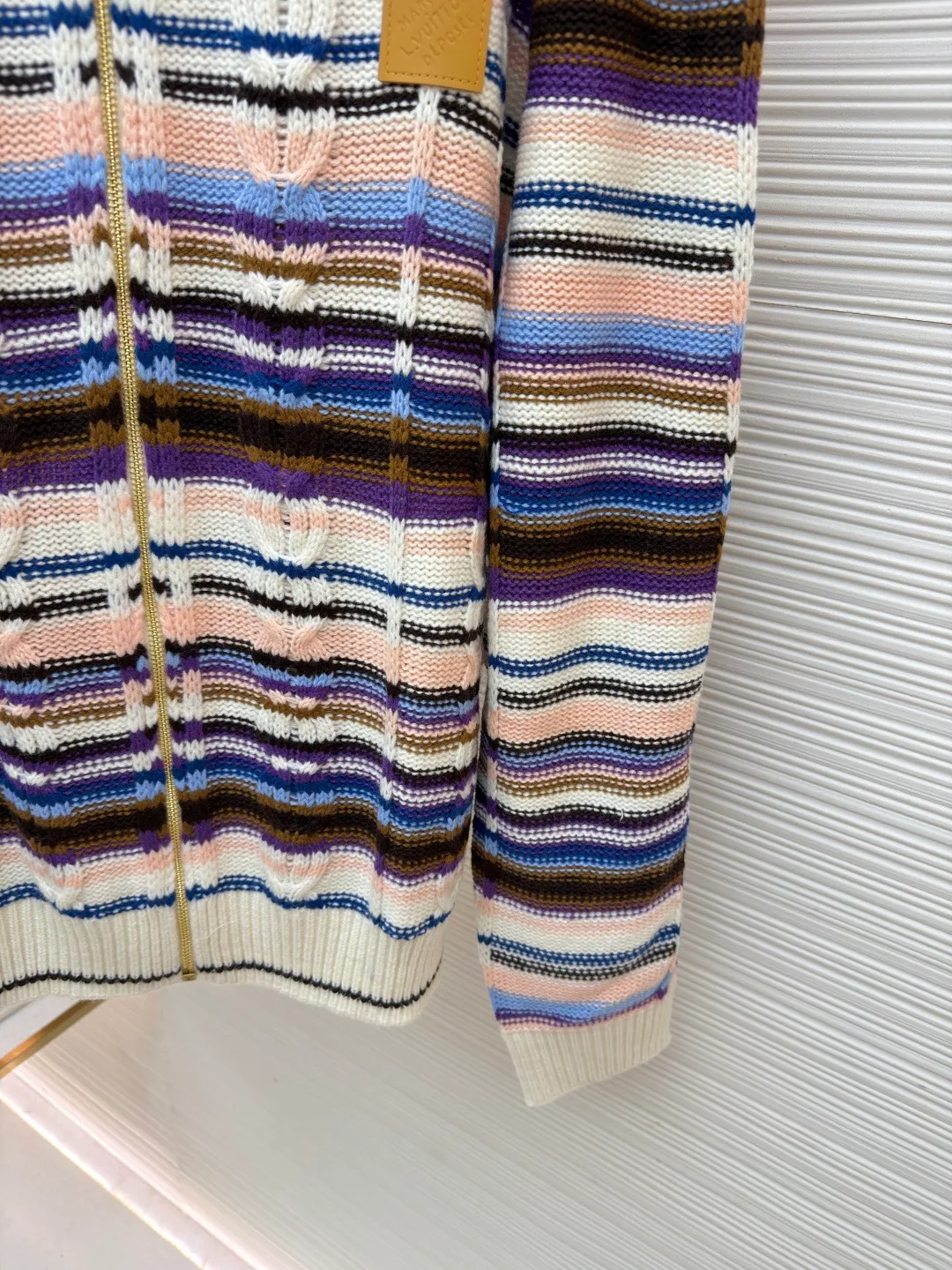 LOUIS VUITTON letter badge color block cable zipper knitted jacket ●Original version: purchased and developed by 21570 ●Item number: 1682322-C15 ●Fabric: wool blended fabric ●Technology: knitting ●Color: pattern ●Version: fitted version ●Weight: about 710 grams ●Size: S-M-L-XL ●Description: This Louis Vuitton color-blocked striped knitted cardigan is made of merino wool and cashmere blended yarn and is woven on a 12-needle coarse-gauge computerized flat knitting machine. The body is interlaced with cable knitting and plain knitting. The stripes are directly knitted with colored yarns instead of post-printing and dyeing. The ratio of colored yarns for each stripe is accurately calculated, making the color transition natural and not easy to fade. The placket is equipped with a customized brass zipper, and the zipper teeth are polished and gold-plated, which is both smooth and durable. The leather label on the left chest is fixed with first-layer calfskin through heat embossing process, and the edges are hand-polished without burrs. The neckline is designed with a high-elastic ribbed stand-up collar, which is not easily deformed after being shaped at high temperatures. The ribbed edges on the cuffs and hem are woven with double-strand yarn, which is more elastic. The shoulders are seamlessly woven with raglan sleeves to reduce the feeling of seams rubbing against the skin. The overall loose fit is combined with three-dimensional tailoring, which not only retains the soft texture of knitting, but also creates a crisp silhouette. Each piece is hand-ironed and quality-checked by brand craftsmen. The overall wiring is straight and delicate, the fabric is comfortable and soft, and the color is consistent without color difference. It can be matched with the same style to create a fashionable look and control various occasions. Customized accessories, complete with three standards, same style for men and women!